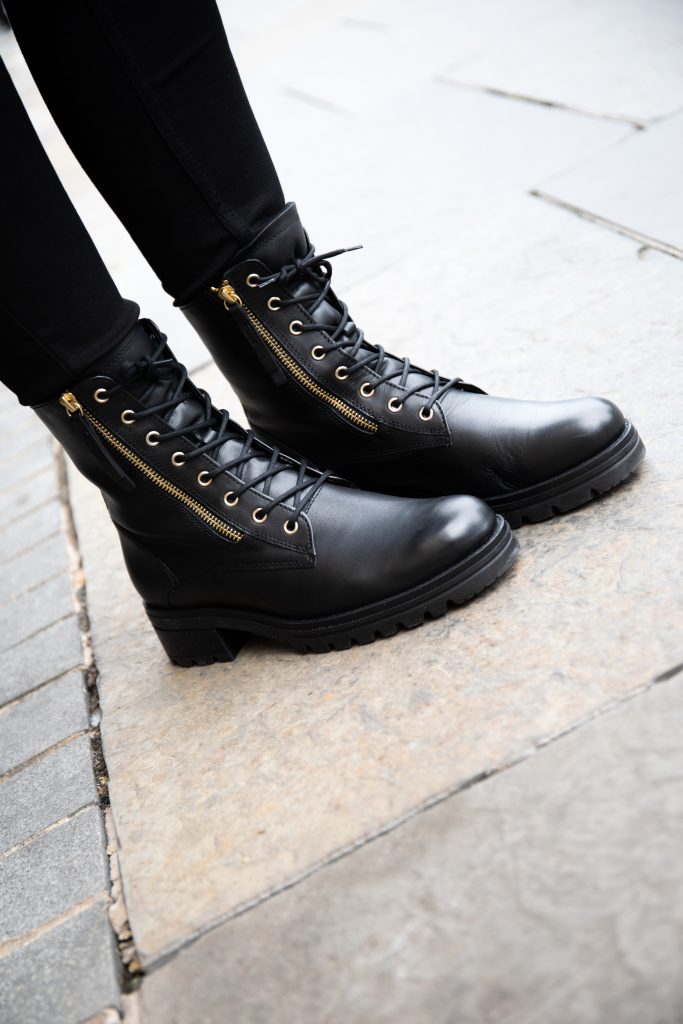 A close-up image of a woman wearing black wide fit boots