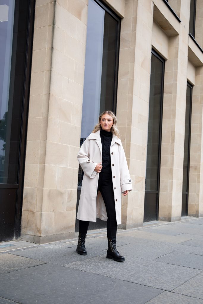 A woman walking across the pavement wearing wide fit boots