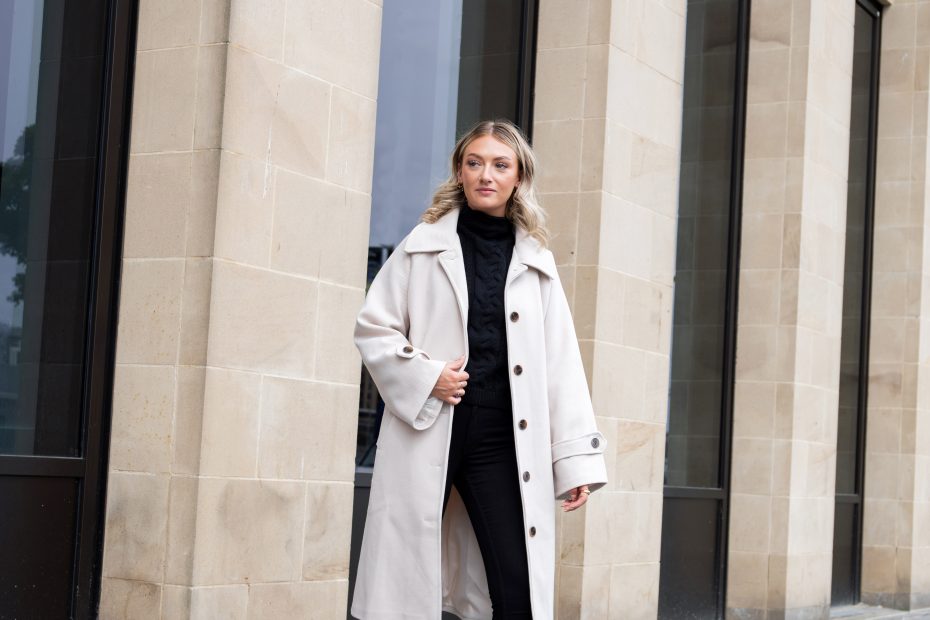 A woman walking across the pavement wearing wide fit boots