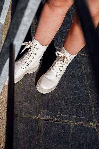 A close up image of a girl wearing a pair of white and cream lace up biker boots