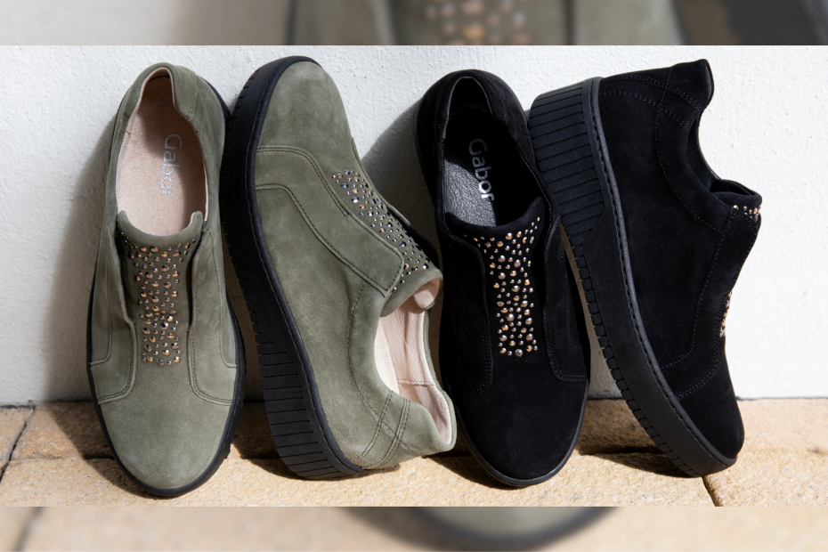 Two pairs of Gabor Wonderland shoes in olive and black suede are set against a white wall.