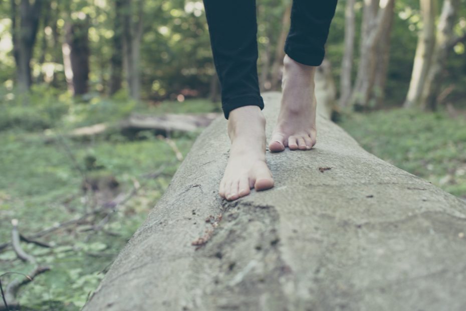 Bare feet climbing on a wooden log.