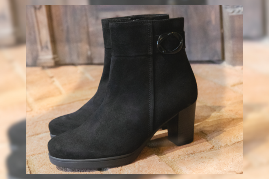 Ankle Boots in black with a heel on a wooden table.