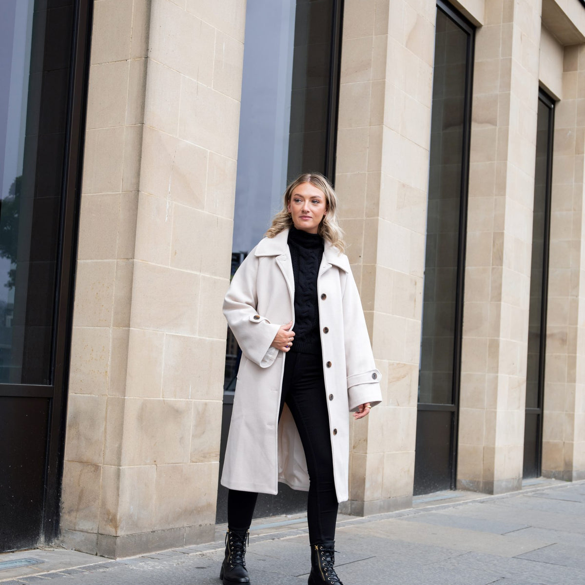 A woman walking across the pavement wearing wide fit boots