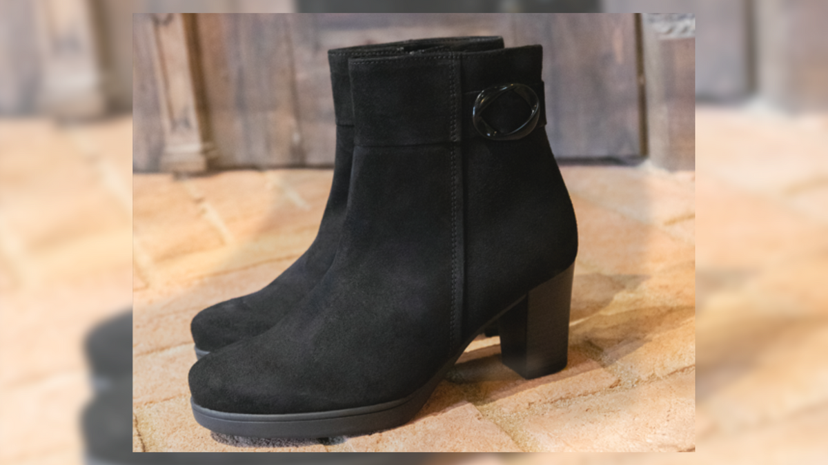 Ankle Boots in black with a heel on a wooden table.