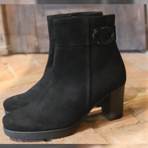 Ankle Boots in black with a heel on a wooden table.
