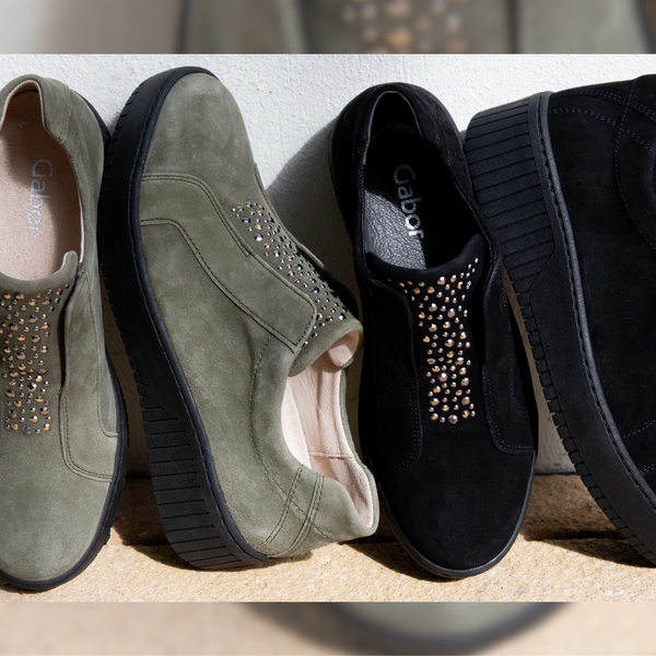 Two pairs of Gabor Wonderland shoes in olive and black suede are set against a white wall.