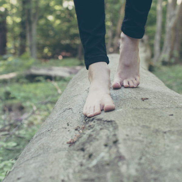 Bare feet climbing on a wooden log.