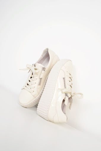 An image of a pair of cream lace-up trainers